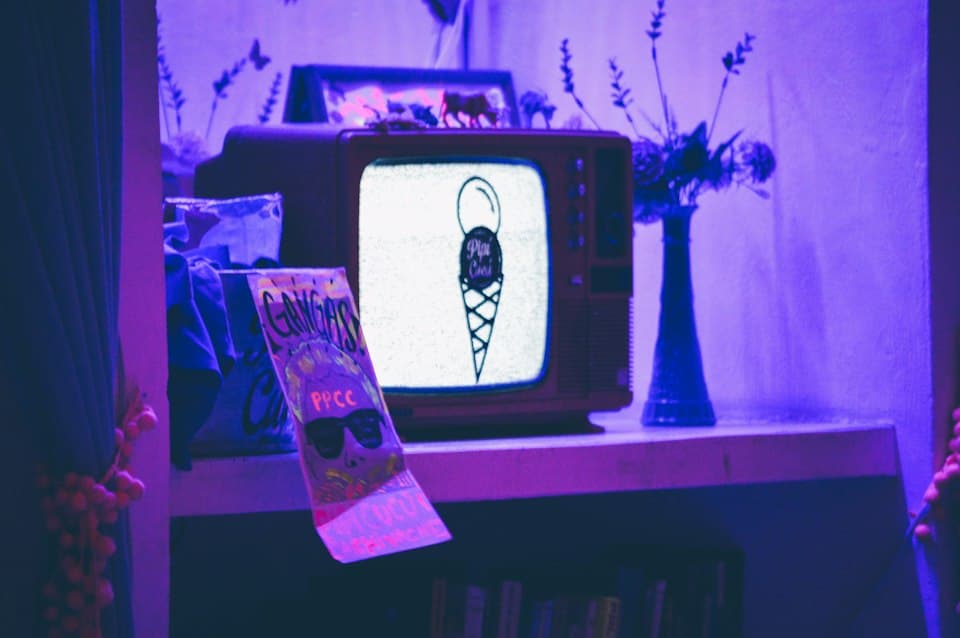 Alter Röhrenfernseher in violettem Licht auf einem Regal