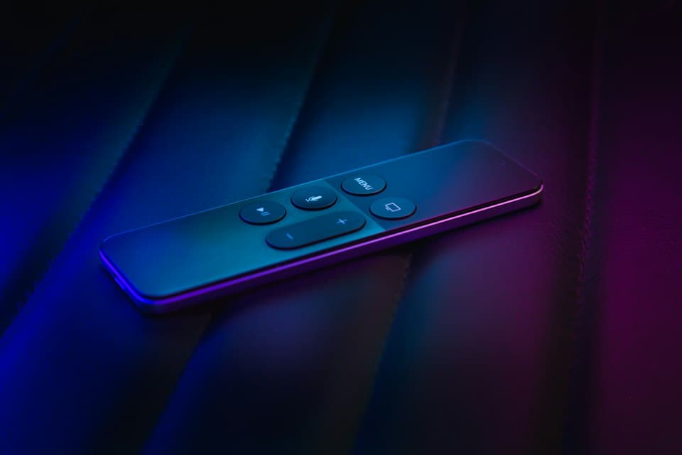 Streaming-Fernbedienung auf dunkler Oberfläche in violett-blauem Licht