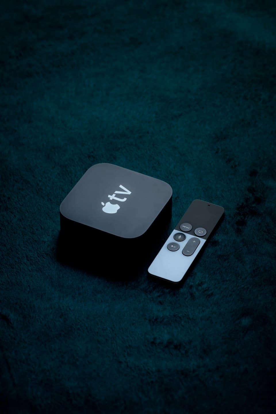 Apple-TV-Box mit Siri Remote auf dunklem Untergrund