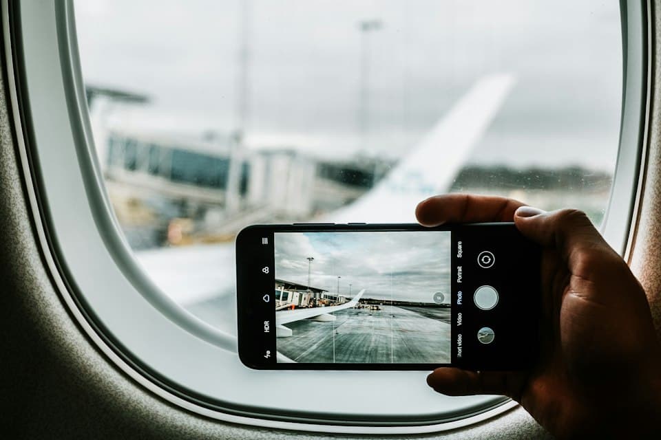 Hand fotografiert mit dem Smartphone durch ein Flugzeugfenster