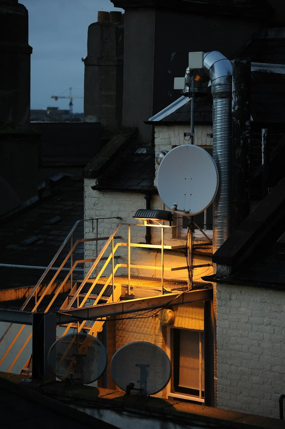 Satellitenschüssel auf einem beleuchteten Dach bei Nacht