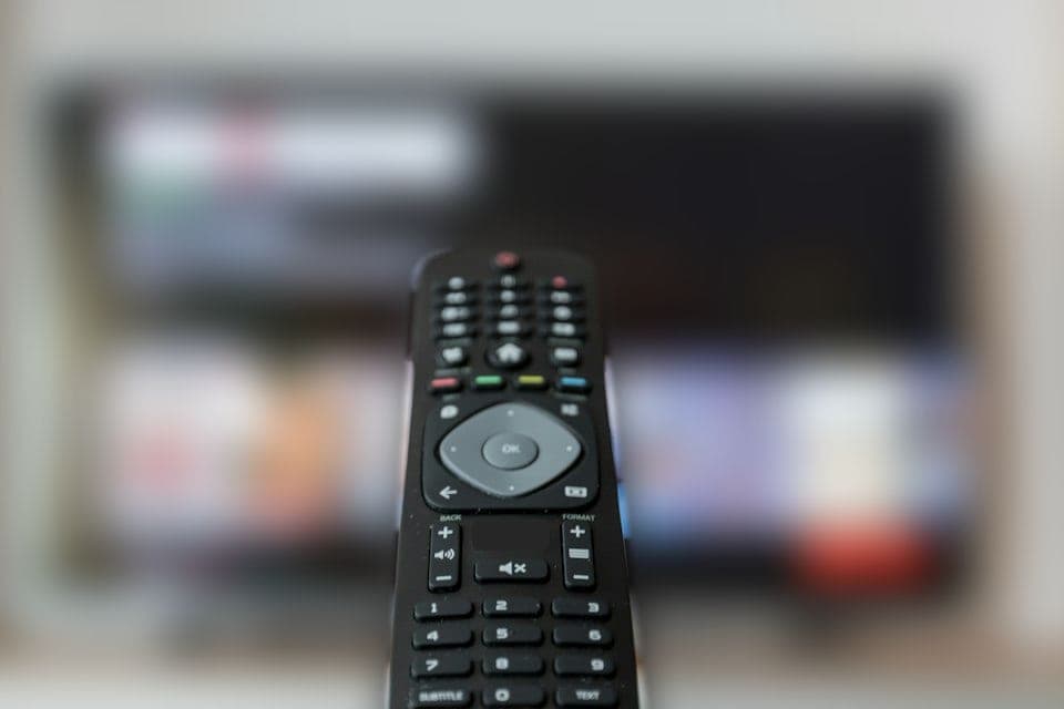Fernbedienung vor einem unscharfen Fernsehbild