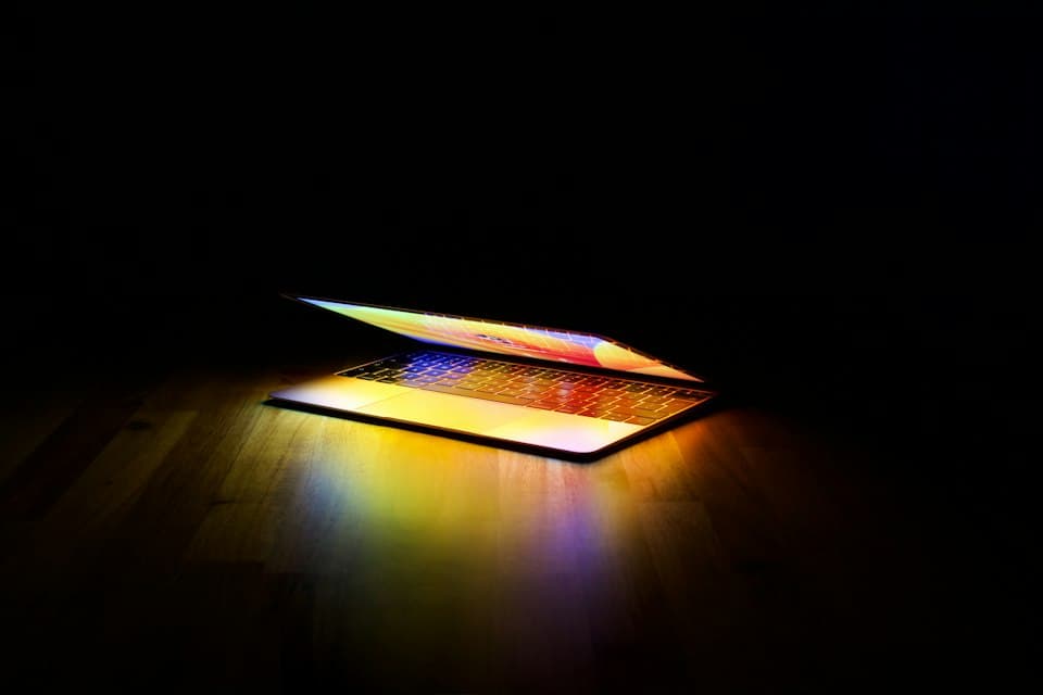 Aufgeklappter Laptop, der im Dunkeln farbig leuchtet